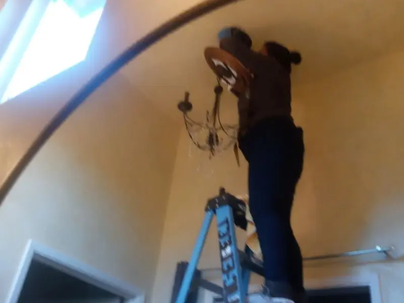 Electrician installing a chandelier in a Alvarado residence